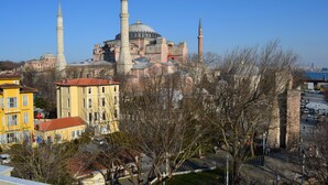 A historic building with multiple minarets and domes, surrounded by modern buildings and a park. - Ares Hotel Sultanahmet (Istanbul)