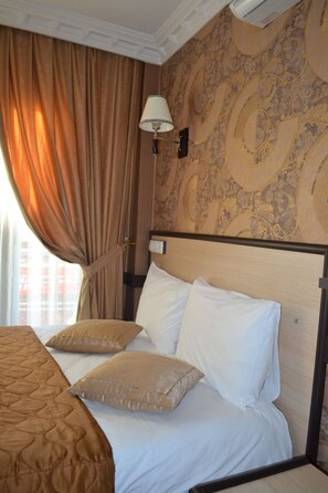 A hotel room with a bed, beige curtains, a wall-mounted lamp, and patterned wallpaper. - Ares Hotel Sultanahmet (Istanbul)