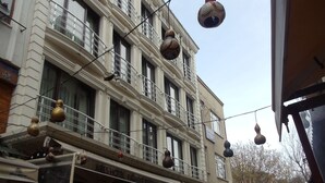 A building with multiple balconies, a restaurant named "Ares Hotel Palmiye Restaurant & Cafe" at the ground level, and hanging decorative spherical ornaments. - Ares Hotel Sultanahmet (Istanbul)