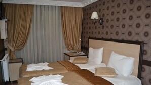 A hotel room with two beds, a nightstand with a lamp, and a patterned wallpaper. - Ares Hotel Sultanahmet (Istanbul)