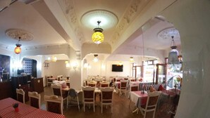 A dining area with multiple tables and chairs, a bar area, and a television screen on the wall. - Ares Hotel Sultanahmet (Istanbul)