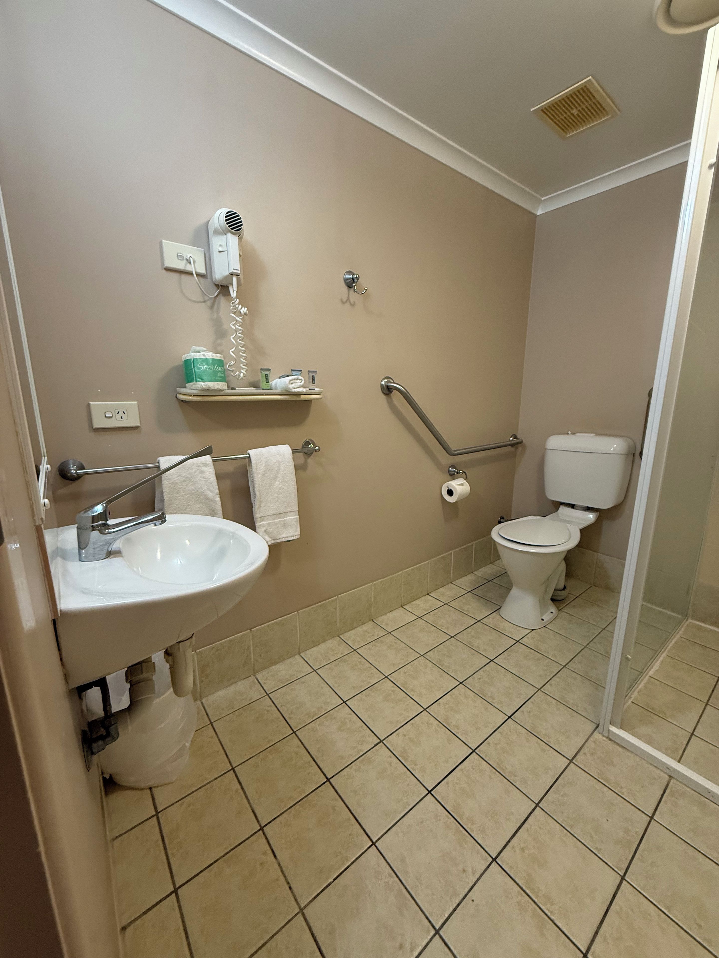 Une salle de bain équipée d’un lavabo, de toilettes et d’un sèche-mains.
