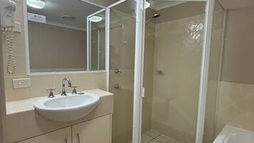 A bathroom with a sink, mirror, shower enclosure, and bathtub.