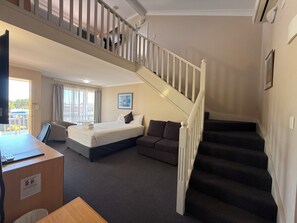 Habitació d'hotel amb un llit, un sofà, una taula i una escala.