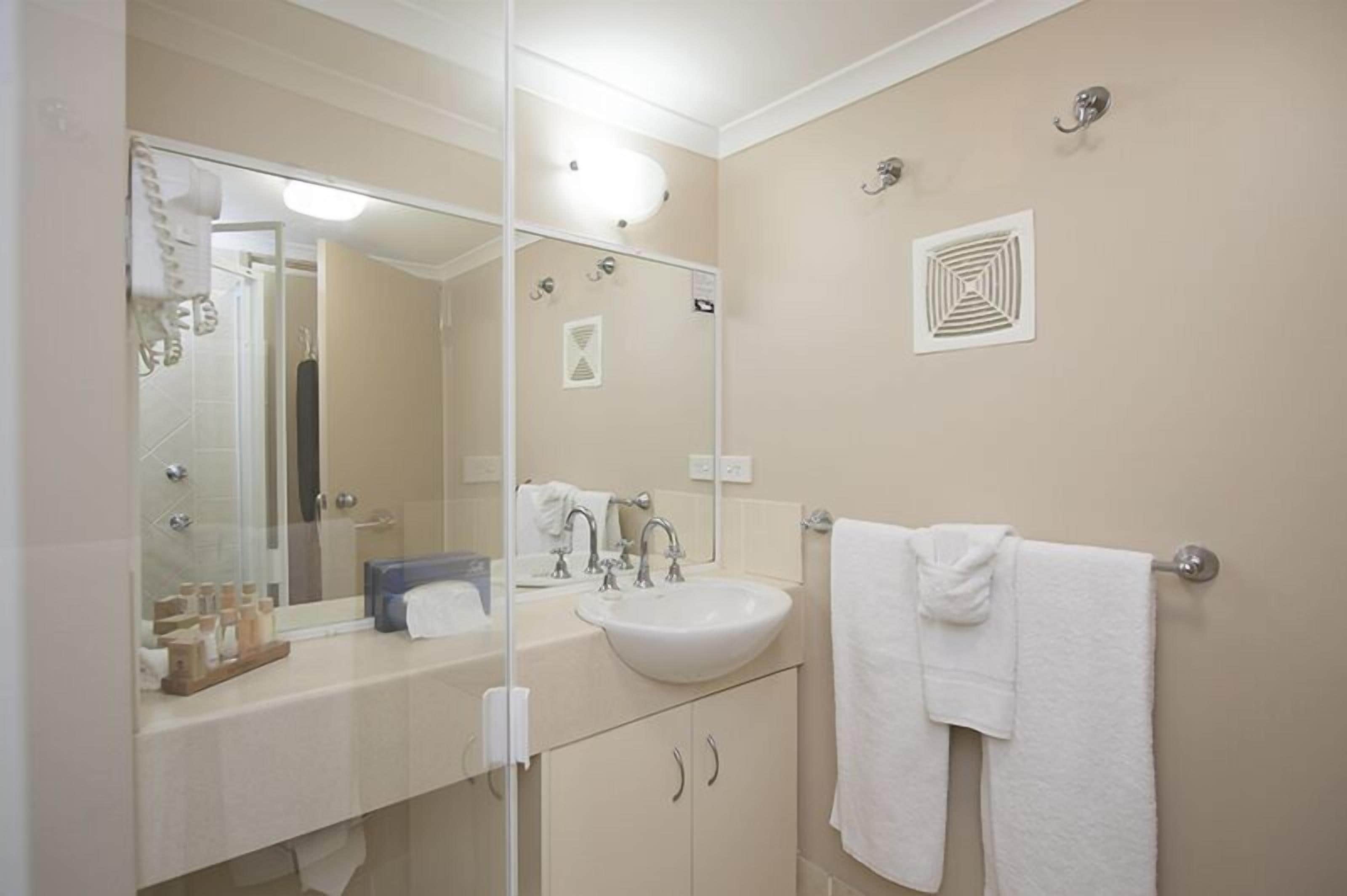 A bathroom with a sink, mirror, towel rack, and toiletries.