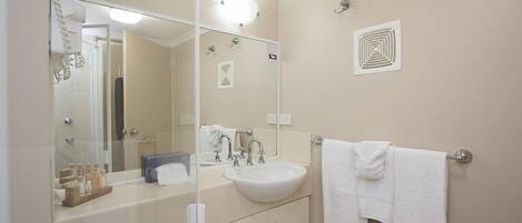 A bathroom with a sink, mirror, towel rack, and toiletries.