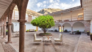 A courtyard with stone flooring, a central tree, and outdoor seating. - La Casona de Yucay Hotel (Yucay)