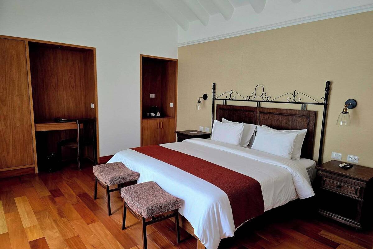 Une chambre à coucher avec un grand lit, deux tables de chevet, un bureau et une armoire.