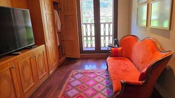 A room with a wooden cabinet, a television, a sofa, and a patterned rug.