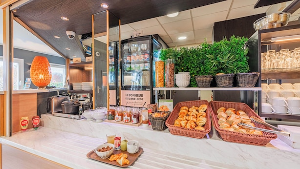A breakfast buffet with various food items, a coffee machine, and a sign in French. - B&B HOTEL Strasbourg Nord Mundolsheim (Mundolsheim)