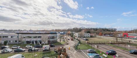 A parking lot with multiple cars and a van, surrounded by buildings and a clear sky.