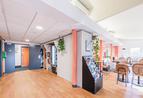 A spacious lobby with a wooden floor, a reception desk, and seating areas.
