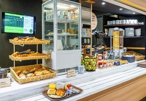 A breakfast buffet with various food items and a digital menu display.