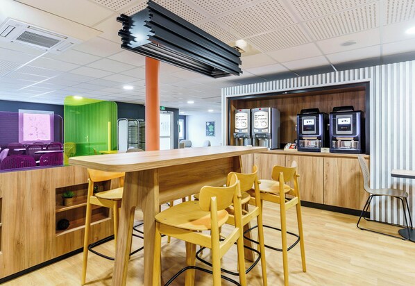 A modern bar area with wooden furniture, a projector screen, and vending machines.