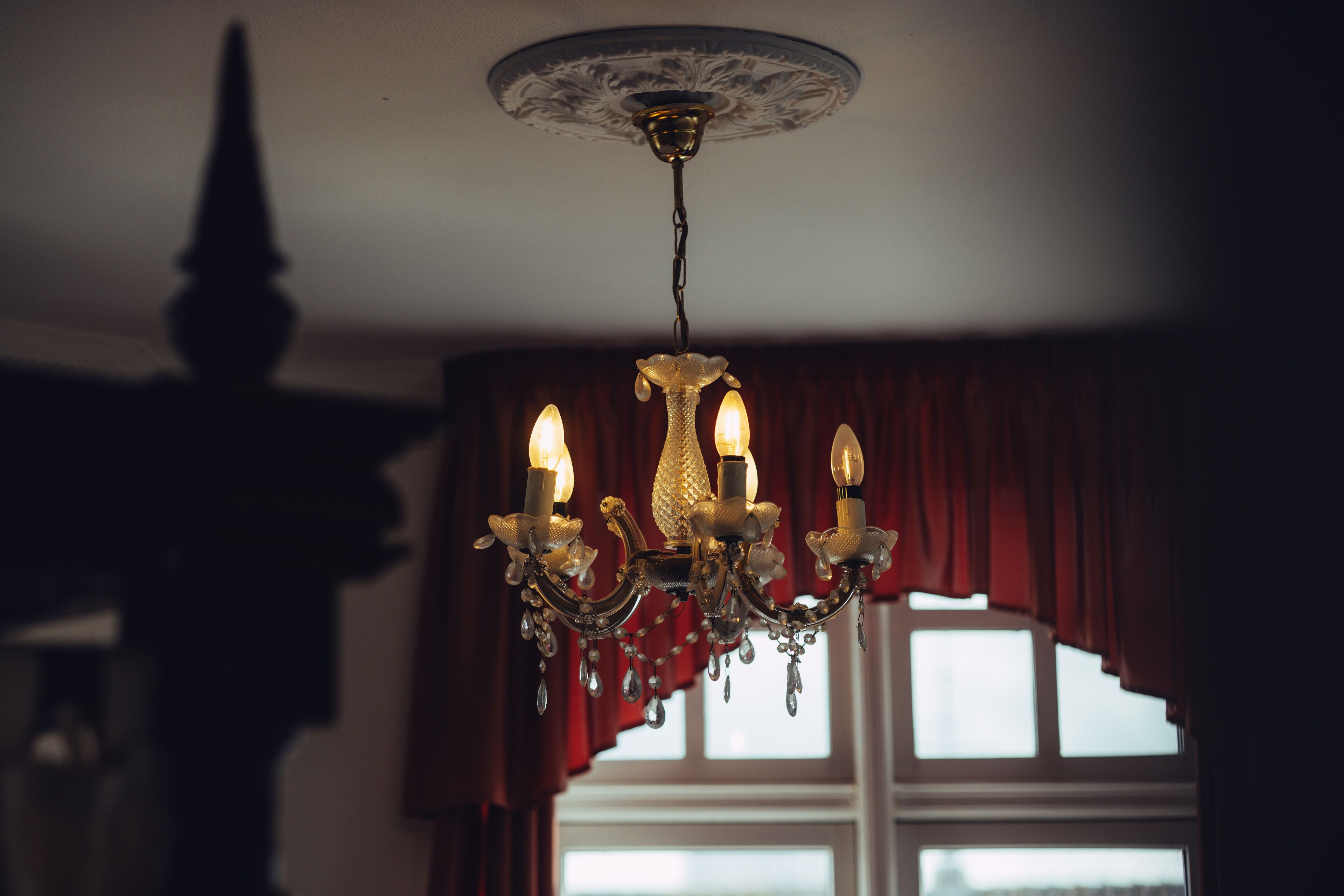 Een kroonluchter met meerdere kaarsachtige lampen en kristaldecoraties.