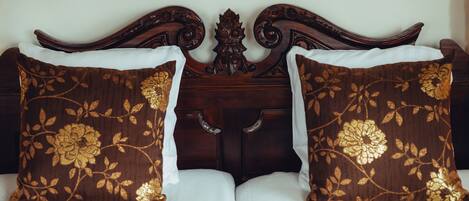 A bed with a dark wooden headboard and two decorative pillows with floral patterns.