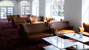 Et hotel lobby med lædersofaer, et glast bord og et rødt tæppe.