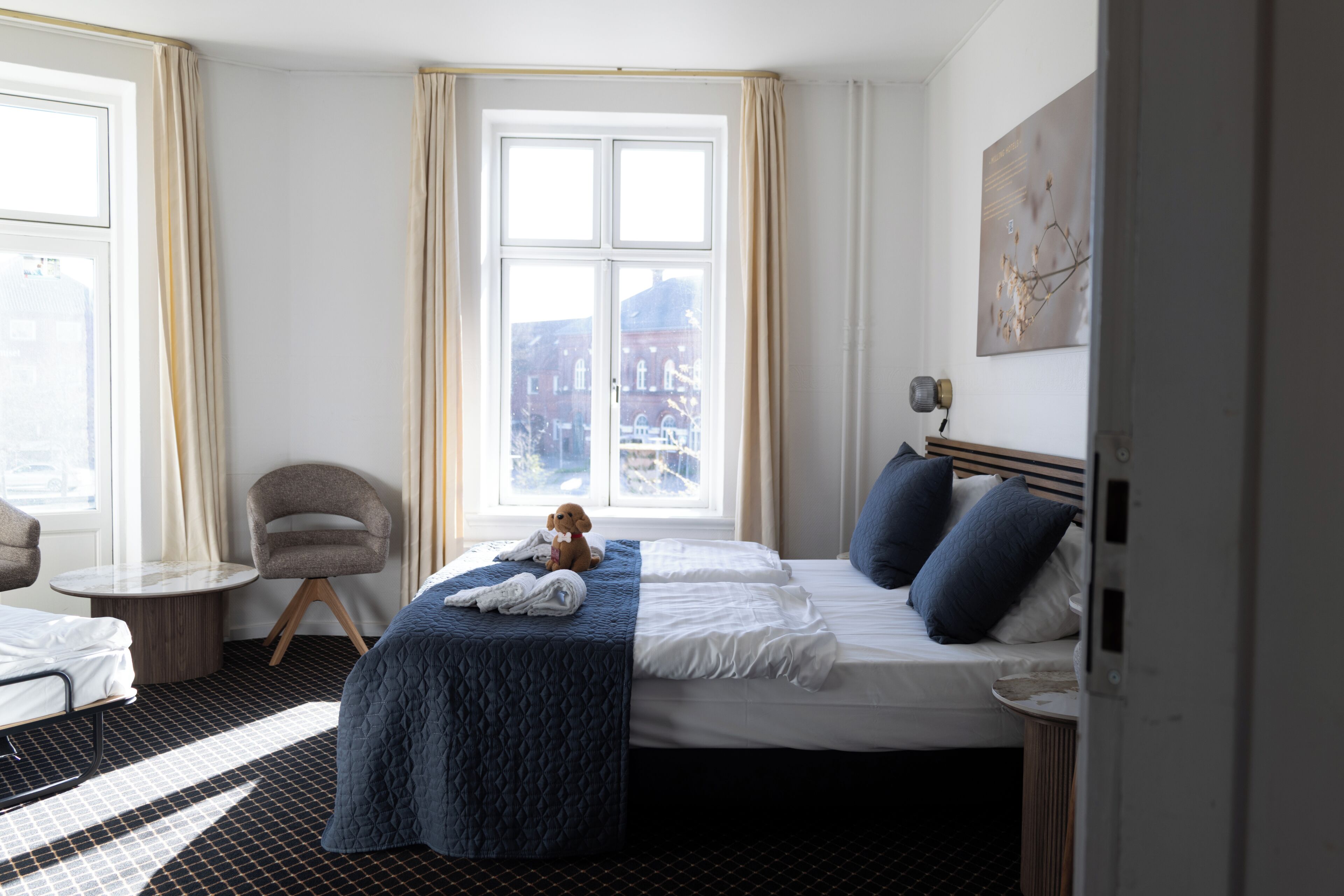 Una habitación de hotel con una cama, una silla, una mesita y una ventana con cortinas.