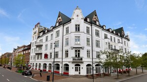En hvid bygning i klassisk arkitekturstil med flere vinduer og en balkon.