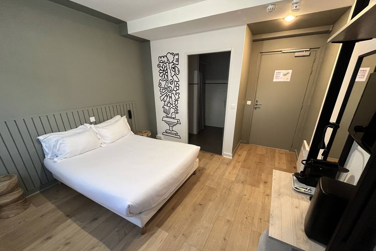 Una habitación de hotel con una cama, un escritorio y un armario.