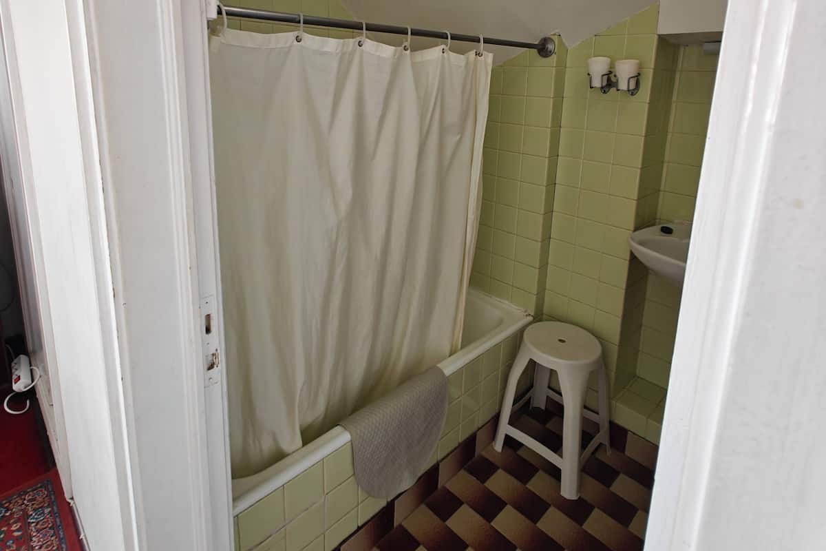 Een bad/douchecombinatie, een regendouche, handdoeken