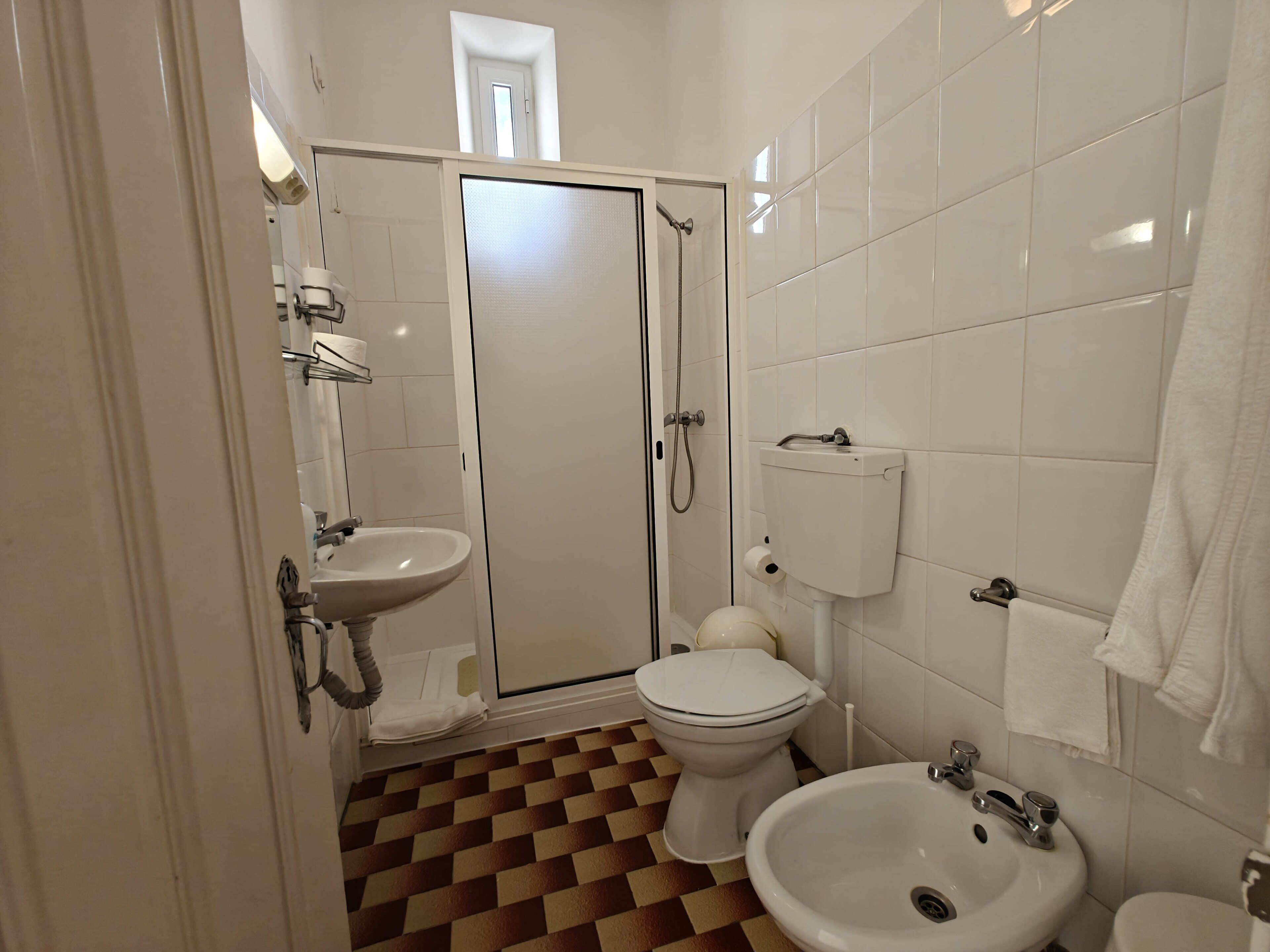 A bathroom with a toilet, bidet, sink, and shower.