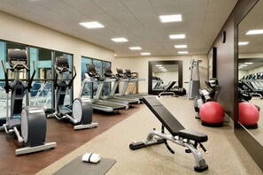 A gym with treadmills, elliptical machines, and exercise balls.