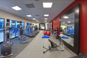Un gimnasio con cintas de correr, elípticas y pelotas de ejercicio.