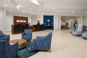 Vestíbulo de hotel con mostrador de recepción, zona de estar y una pared de acento azul.
