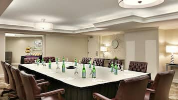 Un salón de conferencias con una larga mesa, sillas y diversos objetos como botellas y vasos.