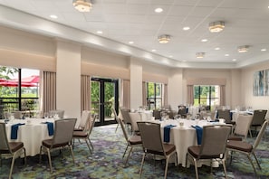 Un salón de banquetes con mesas redondas, sillas y una alfombra estampada.