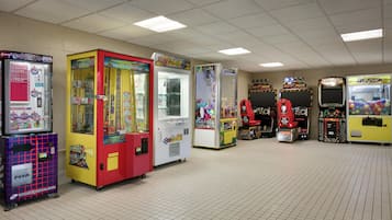 Una hilera de máquinas recreativas en una habitación con suelo de baldosas e iluminación fluorescente.