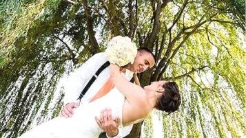 A wedding scene with a couple embracing under a tree.