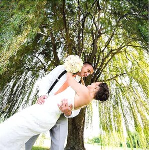 Escena de boda con una pareja abrazándose bajo un árbol.