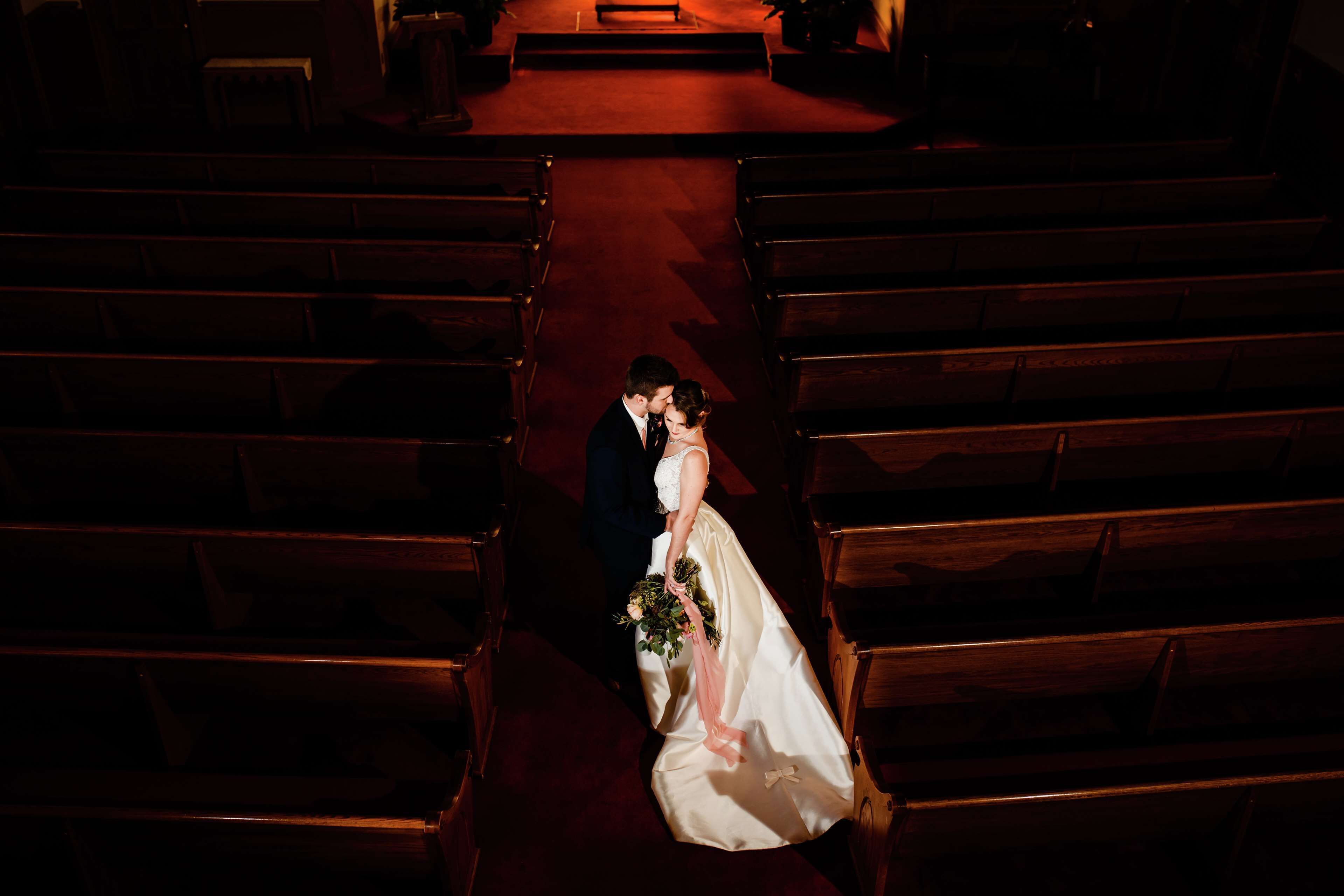 Un couple de jeunes mariés marchant dans la nef d’une église.