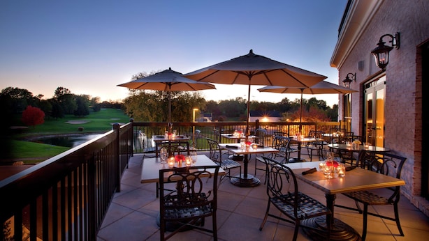 An outdoor patio with tables and chairs, umbrellas, and candles.