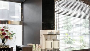 A modern kitchen area with a coffee machine, a vase of flowers, and a dining table with chairs. - Hotel Horidome Villa (Tokyo)