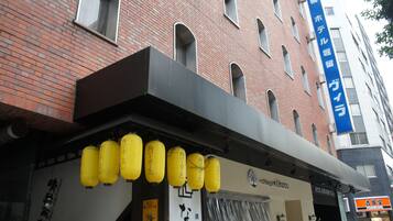 A building with a brick facade, a blue sign with white text, and yellow hanging lanterns.
