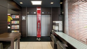 A modern elevator area with a red elevator, a coffee machine, and a vending machine. - Hotel Horidome Villa (Tokyo)