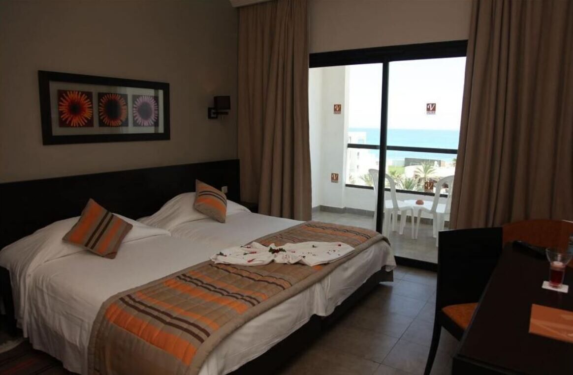 Una habitación de hotel con cama, una mesa de comedor y vista al océano.