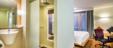 A hotel room with a bathroom, a bed, a desk, and a chair.