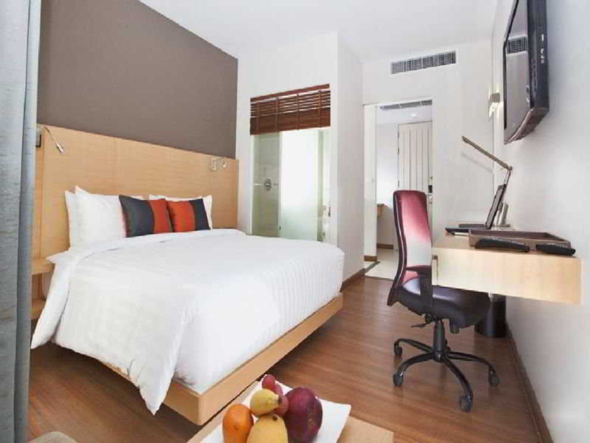 Une chambre d’hôtel équipée d’un lit, d’un bureau, d’une chaise et d’un téléviseur.
