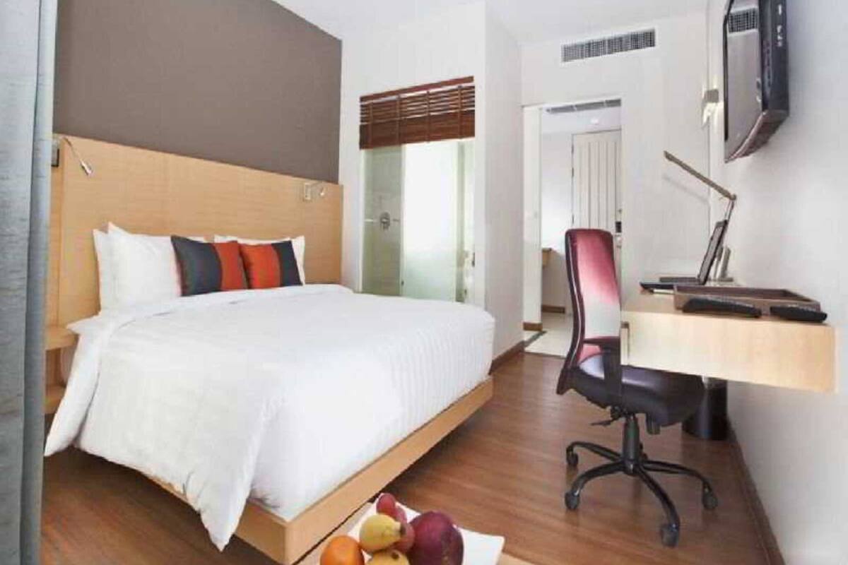 Une chambre d’hôtel équipée d’un lit, d’un bureau, d’une chaise et d’un téléviseur.