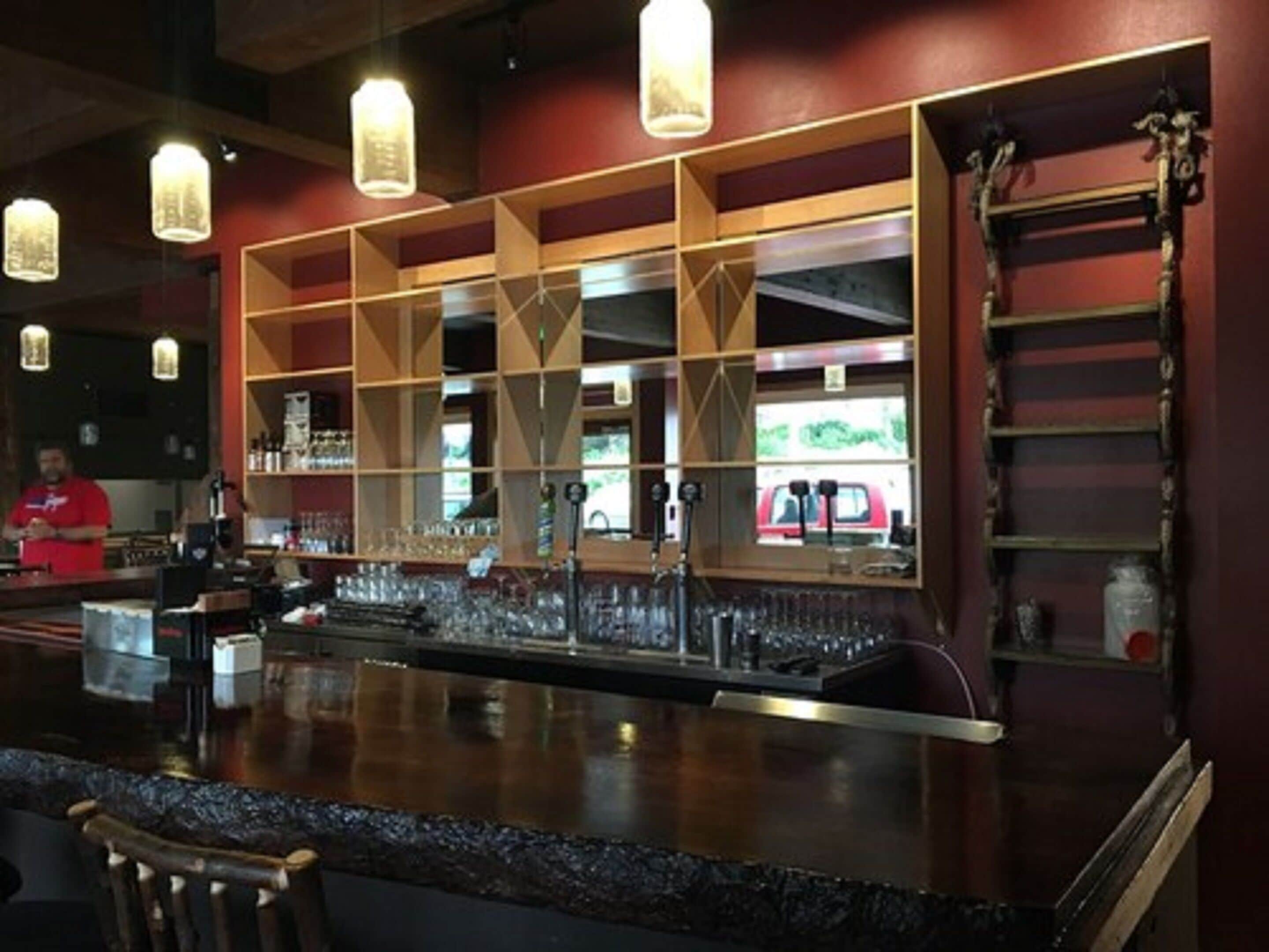 Zona de bar con mostrador, estantes y luces colgantes.