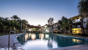 Une piscine offrant une vue dégagée sur les bâtiments environnants et les palmiers.