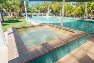 Una piscina con solárium de baldosas y zona de hidromasaje.
