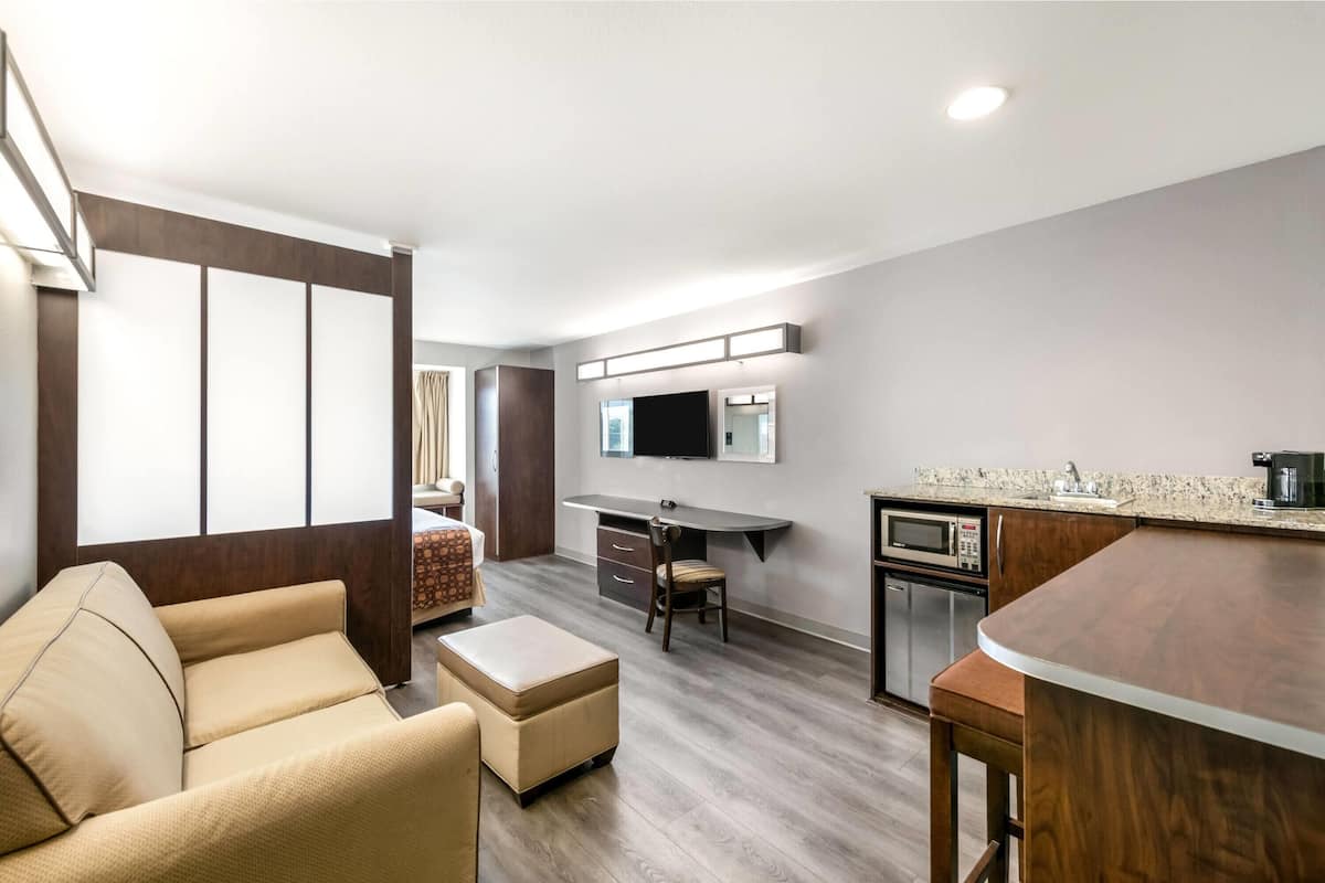 A modern living room with a sofa, ottoman, and a dining area with a bar.