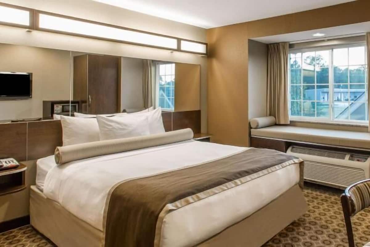 A hotel room with a large bed, a television, a window with a view, and a desk with a chair.