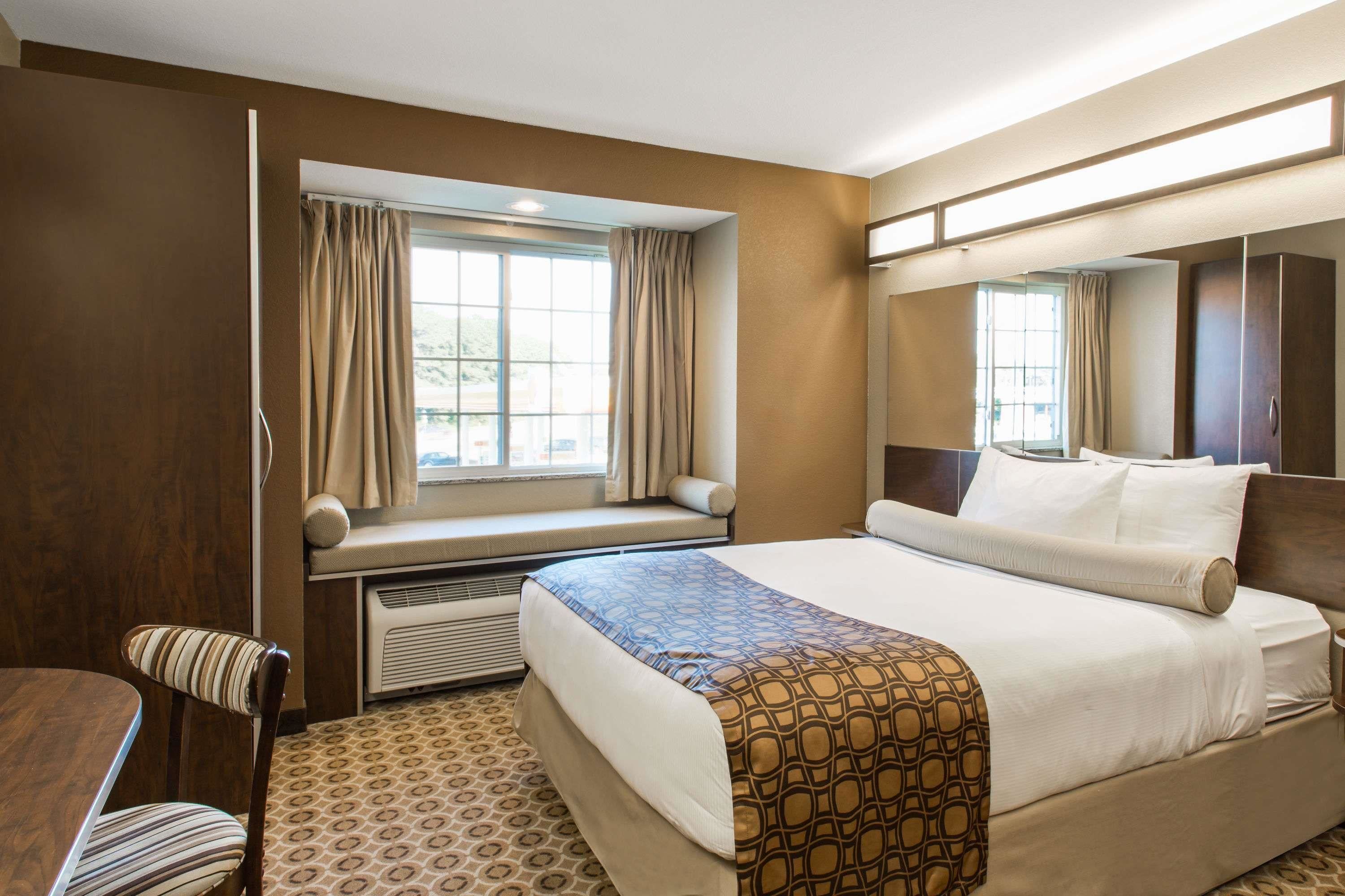A hotel room with a bed, a window seat, a chair, and a wardrobe.