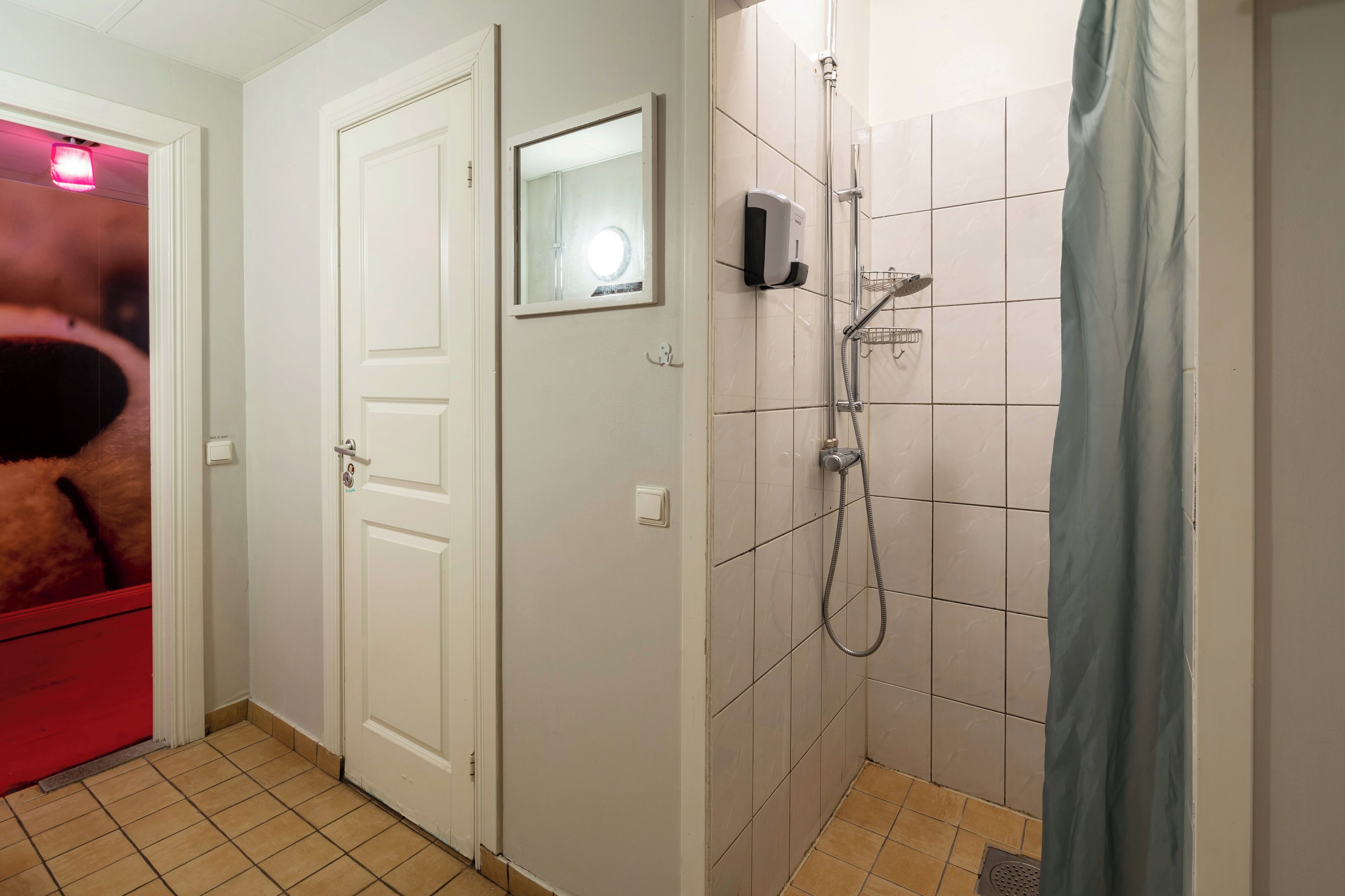 A bathroom with a shower, a mirror, and a hand dryer.